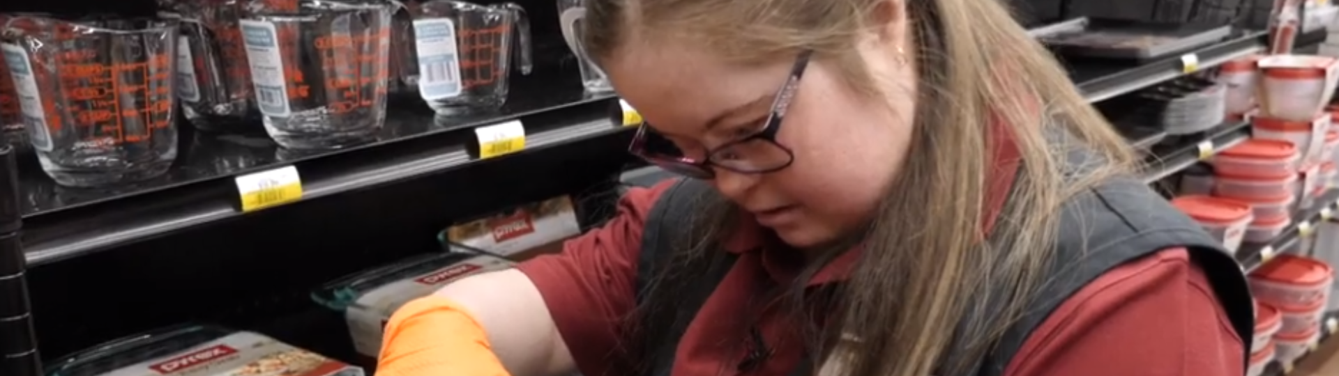 A young woman with Down syndrome adds a price sticker to an item in a store