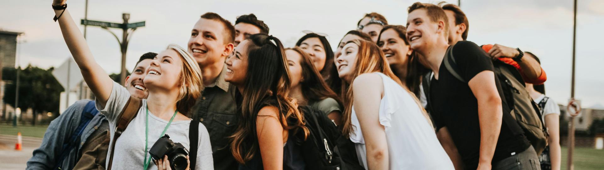 College students smile in a group to take a group selfie