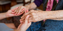 photo of hands of an older and younger person holding one another